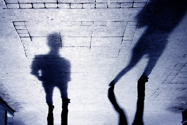 Upside down shadow of two person on pattered sidewalk, in black and white
